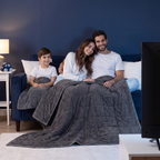 Famille sur le canapé sous les couvertures lestées parents et enfant
