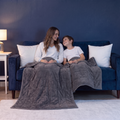 Parent et enfant sur le canapé sous leurs couvertures lestées